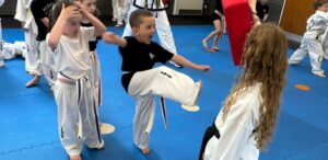 Little Dragons martial arts training Hitchin student performing a kicking drill on a pad